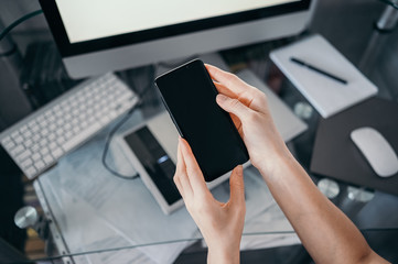 Female hands using smart phone in interior workplace, freelance business woman using cell phone at office desk, working from home using smart phone and notebook computer. Remote worker quarantine