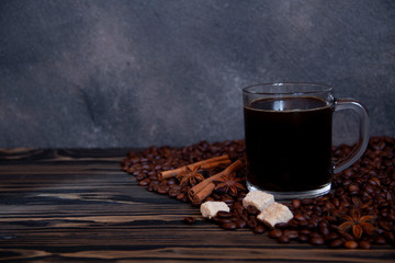 Cup with americano and coffee beans on a wooden table. Copy space for your text.