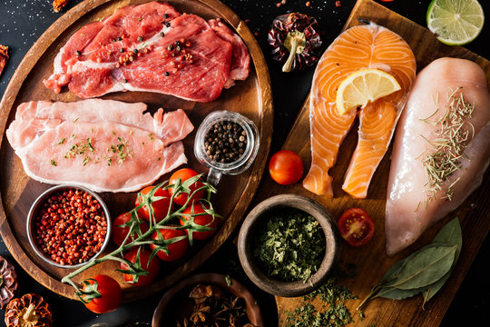 Flat lay of proteins surrounded by spices and seasonings on table