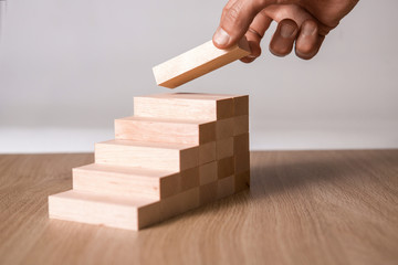 Male hand stacking wooden blocks. Business development and growth concept