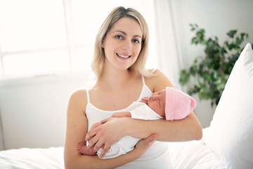 Obraz na płótnie Canvas A woman with a newborn baby in bed