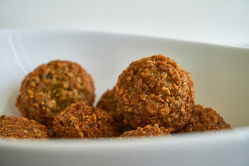 Close-up of fresh and crispy falafels balls inside a white bowl, authentic deep fried chickpea hot round falafels