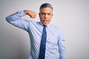 Middle age handsome grey-haired business man wearing elegant shirt and tie Strong person showing arm muscle, confident and proud of power
