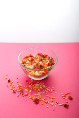 Glass jar with yellow lentils on a pink background.