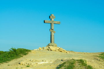 Wooden cross on a hill against the blue sky
