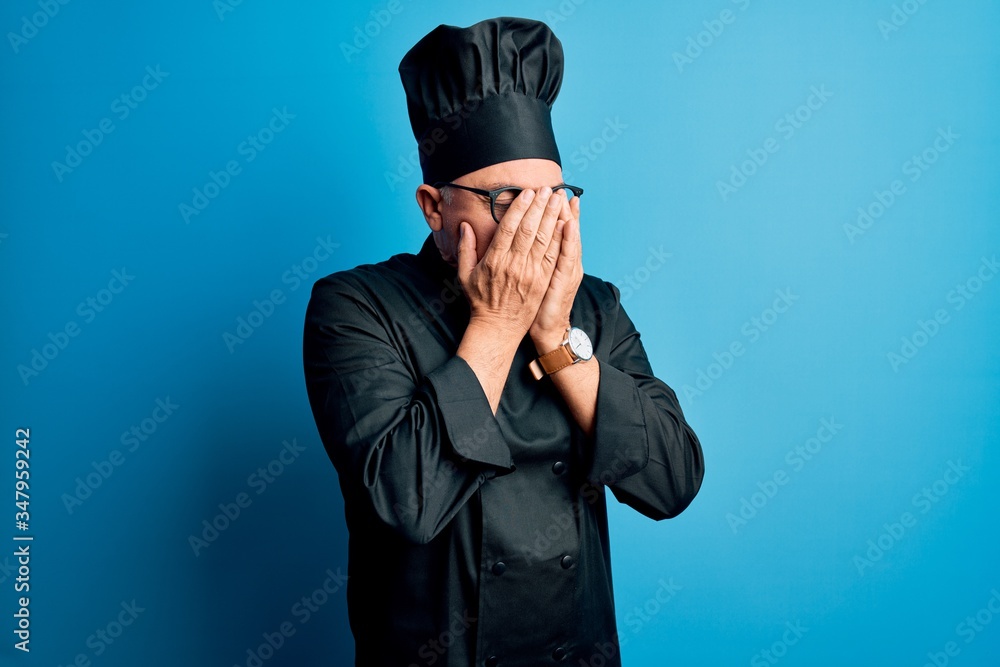 Poster Middle age handsome grey-haired chef man wearing cooker uniform and hat with sad expression covering face with hands while crying. Depression concept.