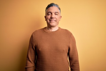Middle age handsome grey-haired man wearing casual sweater over yellow background with a happy and...