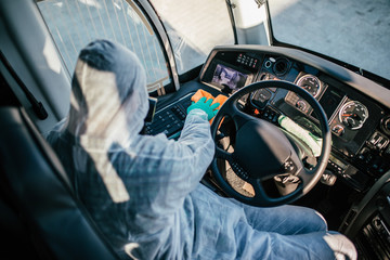Professional driver cleaning a bus in protective workwear as a prevention of Covid - 19, coronavirs.