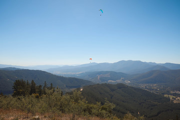 Fototapeta na wymiar View of rolling hills with skydivers in view on bright sunny day