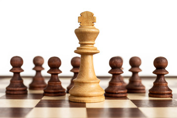 White king surrounded by black pawns. Concept picture taken in studio concerning decision making, strategy, challenge and conflict.