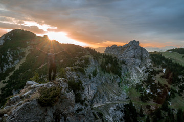 A man stands on the rock at sunrise in the Alps
