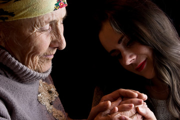 A girl examines the wrinkles on her grandmother's old hands closeup portrait photo. Grandmother and granddaughter hold hands. Caring for elderly parents. Appreciate family and family