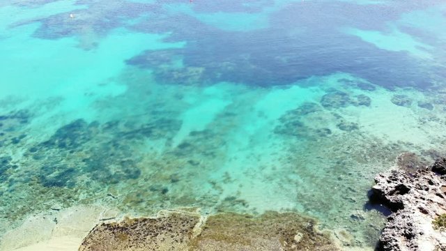 Overflight on transparent seabed with sand rocks and poseidonia