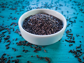 Granulated chocolate brigadeiro in white bowl. Blue background