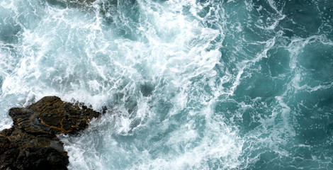 Roaring waves breaking on rocks cliff in Cinque Terre, Liguria, Italy. View from above.