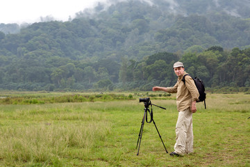 man with a camera on a tripod on a background of a mountain with a tropical forest. Bali. Indonesia.