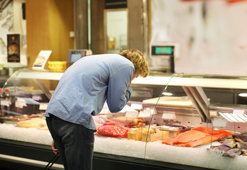 man shopping for fresh fish seafood in supermarket retail store