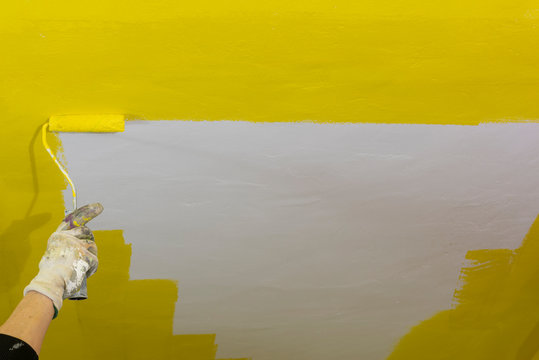 Pintor con rodillo de pintura, pinta el techo de amarillo