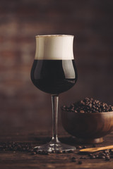 Irish coffee with whiskey. Alcoholic warming cocktail with foam from cream and coffee beans on it.