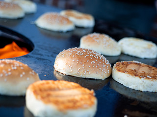 Close up of some burger buns roasting on a fire plate.