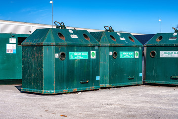 Close up photo of large public recycling green metal containers at parking lot for disposal of...