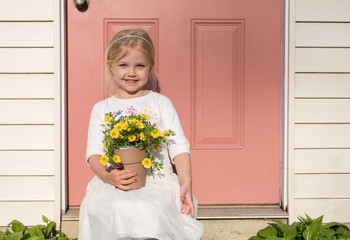 Little girl holding a pot of yellow flowers
