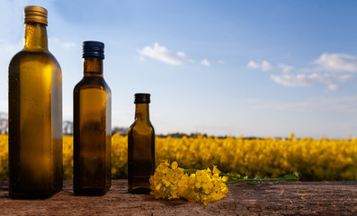 Rapeseed oil (rapeseed) and rapeseed flowers on a wooden board.