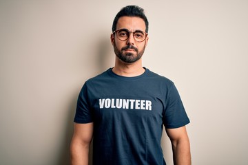 Handsome man with beard wearing t-shirt with volunteer message over white background Relaxed with serious expression on face. Simple and natural looking at the camera.