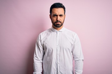 Young handsome man with beard wearing casual shirt standing over pink background skeptic and nervous, frowning upset because of problem. Negative person.
