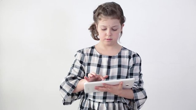 Child's school lifestyle during Covid 19. A smiling happy schoolgirl in headphones with a pink computer laptop lies on the sofa, studies online, enjoys music, uses the calling application, reads, e