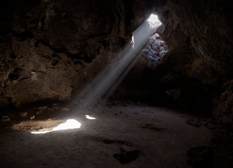 Sunlight shines from above into a small cave in the Mojave desert, California, USA