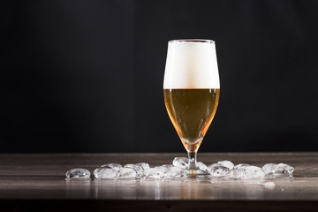 A glass of light beer is on the table with ice. The concept of relaxation, bars and parties