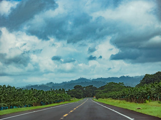 down the road in the middle of the mountains with cloudy sky