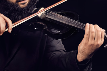 Musician playing a black violin on a black background