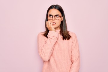 Young beautiful brunette woman wearing casual sweater and glasses over pink background looking...