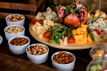 Close view of jamon rolls, cherry tomatoes, nuts and dried apricots served for festive occasion