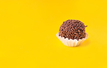 Brigadeiro (Brigadier) a Brazilian chocolate candy. Traditional Brazilian handmade chocolate sweet. Isolated on yellow background. 