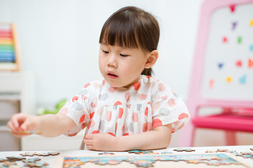 toddler girl playing wooden puzzle at home