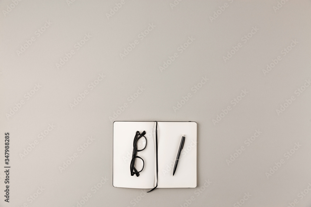 Poster top view of empty abstract gray office desk with notebook and eyeglasses and copy soace