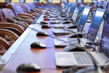 in the large hall, a long table made of wood for negotiations, open computers and microphones at...