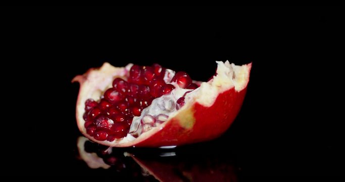 Piece of ripe pomegranate falling into water.