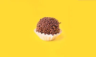 Brigadeiro (Brigadier) a Brazilian chocolate candy. Traditional Brazilian handmade chocolate sweet. Isolated on yellow background. 