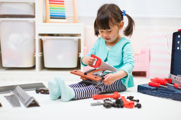 toddler girl pretend using DIY tool at home against white backgrround