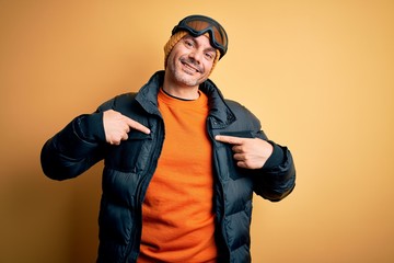 Young handsome skier man skiing wearing snow sportswear using ski goggles looking confident with...
