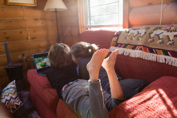 bare feet of young boy and his sister looking at laptop on sofa