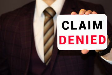 Businessman putting a card with text Claim Denied in the pocket