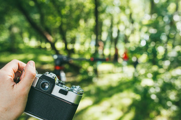 a man's hand holds an old vintage film camera and photographs a green landscape. first-person view POV