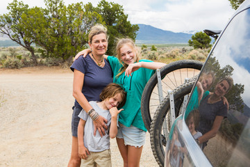 portrait of mother and her children with mountain bikes on back of SUV