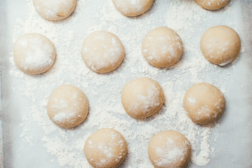 Homemade dough pies on the baking sheet ready for the oven for baking. Selective focus macro shot...