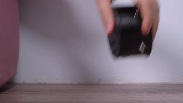 Alarm clock piercingly rings, wakes person early in the morning. Man grabs a watch in hand, hits it on floor, pinches and throws it out so as not to hear this annoying noise and sleep on, close up.